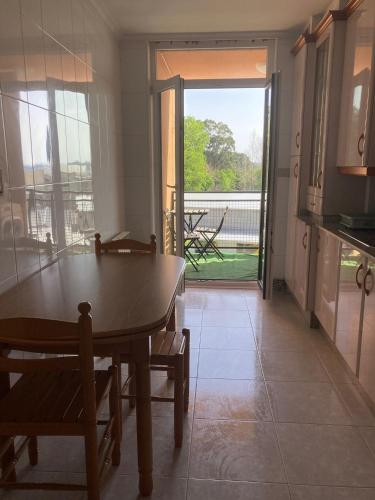 a kitchen with a table and a view of a porch at Refugio Mar de Boiro in Boiro