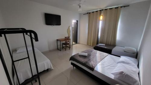 a bedroom with a bed and a chair and a television at Golden Silver UNIQUE in Curvelo