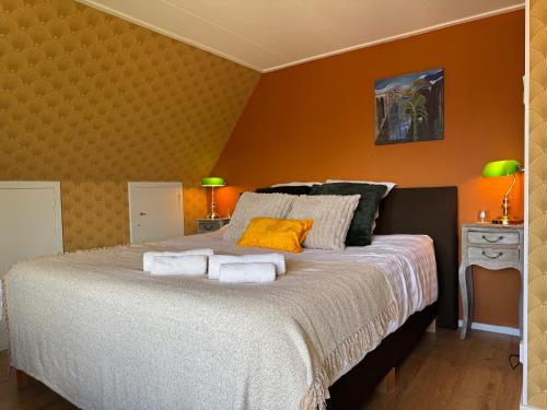 a bedroom with a large bed with orange walls at B&B Pastorie Jelsum in Jelsum