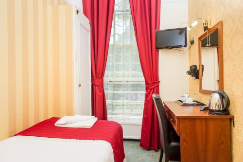 ロンドンにあるエイヴォンモア ホテルのベッド、デスク、窓が備わるホテルルームです。