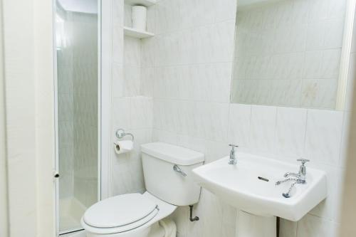 bagno bianco con servizi igienici e lavandino di Avonmore Hotel a Londra