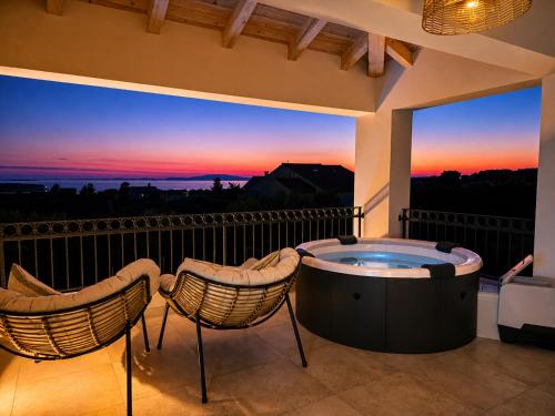 a hot tub on a balcony with two chairs at Villa Lumia in Banjol