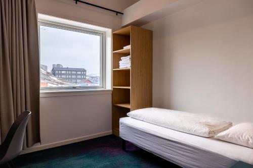 a small bedroom with a bed and a window at Hotel Aurora in Nuuk
