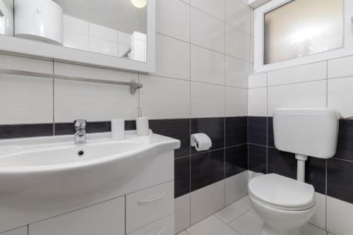 a white bathroom with a toilet and a sink at Apartments with parking space Zavala, Hvar - 8710 in Jelsa