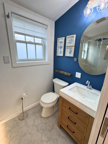 a bathroom with a toilet and a sink and a mirror at Ocean light | Deck + Patio • Central P-Town in Provincetown