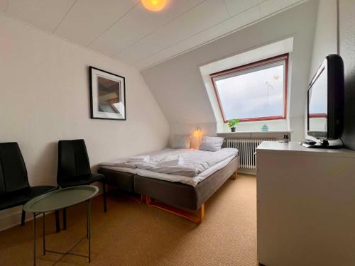 ein Schlafzimmer mit Bett, Fernseher und Tisch in der Unterkunft Sverres Hotel in Rønne