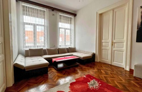 a living room with a couch and two windows at Fuchsl Palace Grand Suite - Ultra Central in Oradea