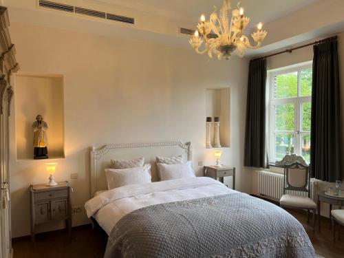 ein Schlafzimmer mit einem Bett und einem Kronleuchter in der Unterkunft De Pastory Peer in Grote-Brogel