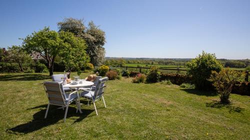 a table and chairs on the grass in a field at Priors Mead Cottage in Claydon