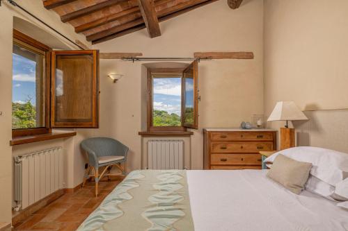 a bedroom with a bed and a chair and windows at Villa Montebella Countryside Retreat in Montepulciano in Montepulciano