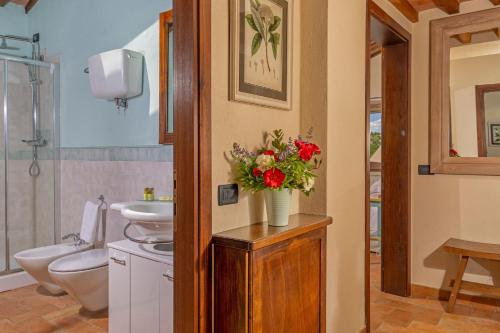a bathroom with a toilet and a vase of flowers at Villa Montebella Countryside Retreat in Montepulciano in Montepulciano