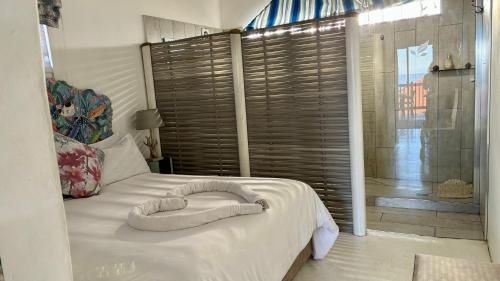 a white bed with a large window in a bedroom at Victorian Beach Cottages in Amanzimtoti