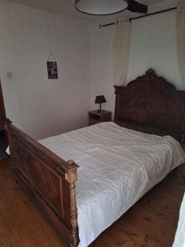 a bedroom with a large wooden bed with white sheets at gite Chèvre in La Chavière