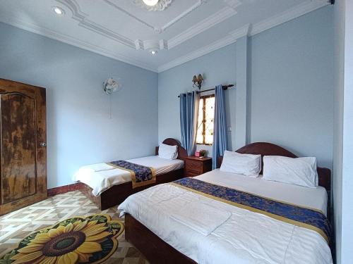 a bedroom with two beds and a window with blue walls at Good Day Kampot Guesthouse in Kampot