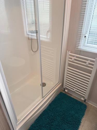 a shower with a glass door and a green rug at Beach View Eden Heights Kinkell Braes 2 bedrooms 2 bathrooms in St. Andrews
