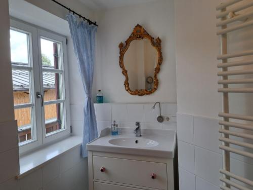 a bathroom with a sink and a mirror and a window at Ferienwohnungen im Lüftlmalereck, Mussldomahaus in Oberammergau