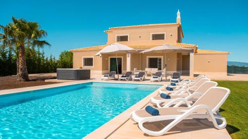 a villa with a swimming pool and lounge chairs at Villa Paradise - Moradia tranquila com piscina aquecível e BBQ - Albufeira in Lagoa