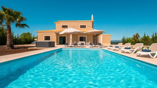a villa with a swimming pool in front of a house at Villa Paradise - Moradia tranquila com piscina aquecível e BBQ - Albufeira in Lagoa