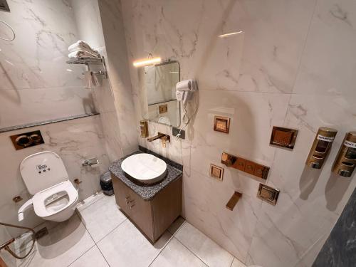 a white bathroom with a toilet and a sink at Hotel Rosewood in Prayagraj