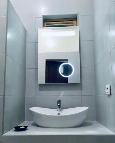 a white bathroom with a sink and a mirror at Le Renala Morondava in Morondava