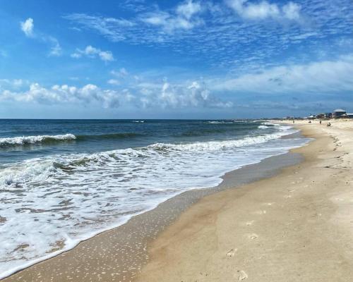 a beach with the ocean and people walking on it at Beachfront 6BR Retreat w Gulf Views Sleeps 16 in Port Saint Joe