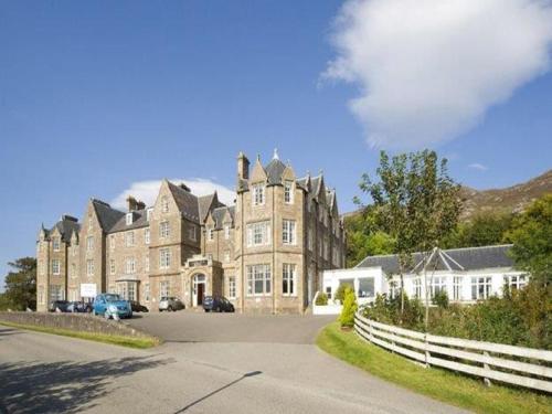 a large building with a fence in front of it at Gairloch Hotel 'A Bespoke Hotel' in Gairloch