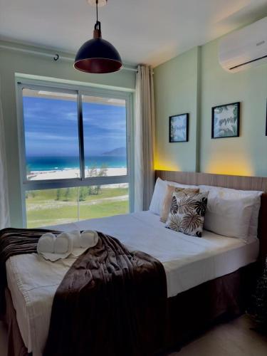 a bedroom with a bed with a view of the ocean at Flat Mandai Cabo Frio in Cabo Frio