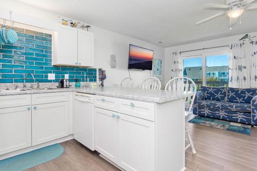 a kitchen with white cabinets and a blue tile wall at Pebble Beach I-211 in Emerald Isle