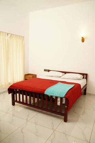 a bedroom with a bed with a red and blue blanket at Twilight Stays Cherai Beach in Pallipuram