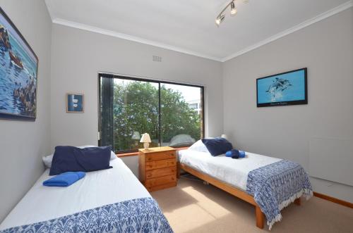 two beds in a room with a window at Cosy House in Yzerfontein