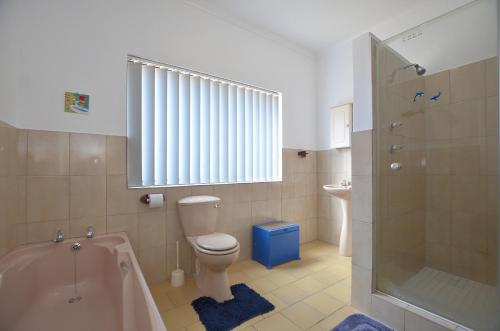 a bathroom with a tub and a toilet and a shower at Cosy House in Yzerfontein