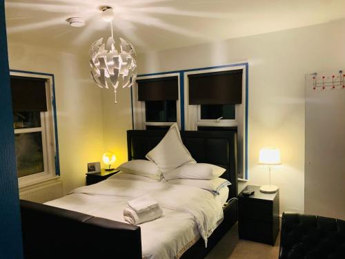 a bedroom with a bed with white sheets and a chandelier at Blue Room in Ifield