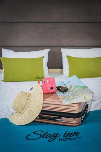 a hat and a camera sitting on top of a bed at Stay inn Hotel Gdańsk in Gdańsk