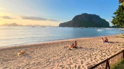 a group of people sitting on the beach at Doublegem Beach Resort and Hotel in El Nido