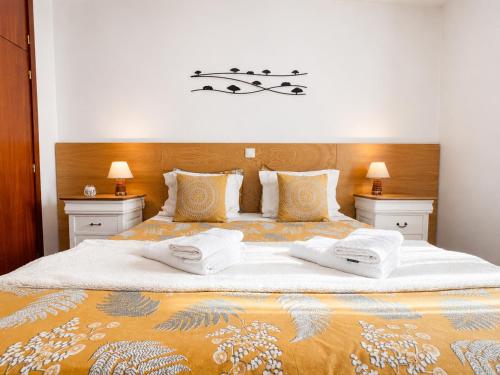 a bedroom with a large bed with two towels on it at Refúgio do Vidoeiro in Geres