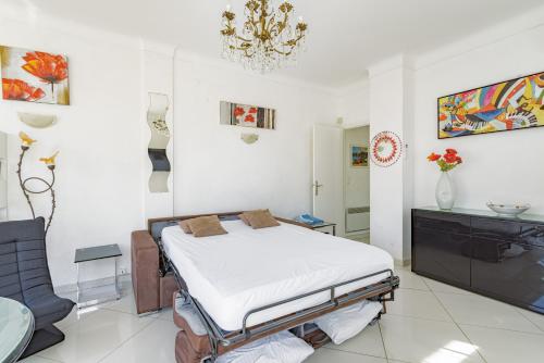 a white room with a bed and a chandelier at Mer Vue Sublime in Canet-en-Roussillon