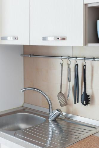 a kitchen sink with utensils hanging on a wall at La casa del sole in Conca dei Marini