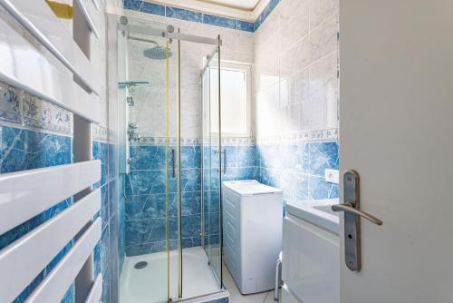 a blue tiled bathroom with a shower and a toilet at Mer Vue Sublime in Canet-en-Roussillon