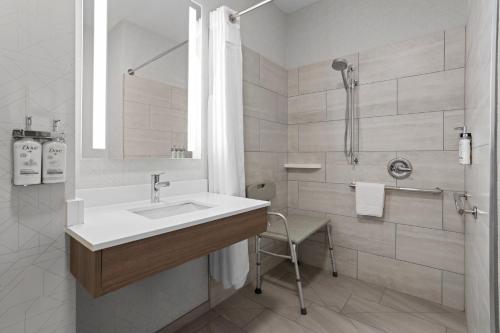 a white bathroom with a sink and a shower at Holiday Inn Express Syracuse-Fairgrounds by IHG in Warners