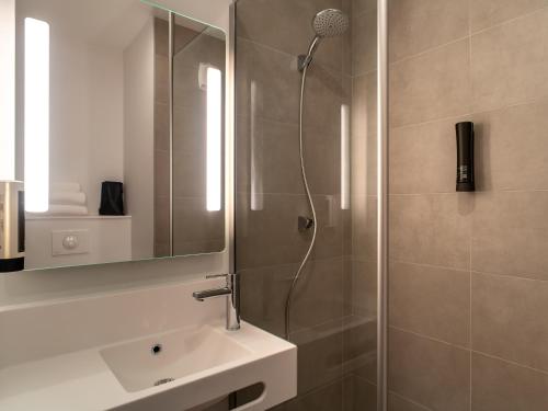 a bathroom with a shower with a sink and a mirror at B&B HOTEL Concarneau Keriolet in Concarneau
