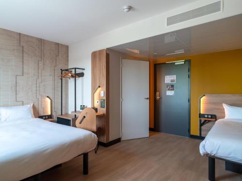 a hotel room with two beds and a hallway at B&B HOTEL Concarneau Keriolet in Concarneau