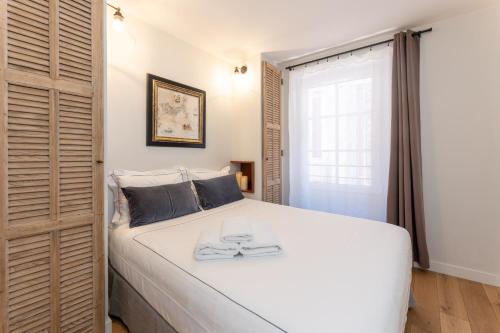 a bedroom with a large white bed and a window at Les Petits Volets Appartements à 100m de la mer in Antibes