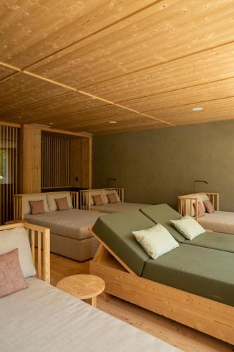 three beds in a room with wooden ceilings at Vitalpina Hotel Schulerhof in Plaus