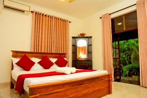 a bedroom with a bed with red pillows and a window at Hamilton View in Negombo