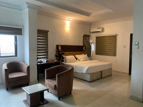 a bedroom with a bed and a desk and a chair at Aotel Hotels & Suite - Ipaja in Asipa