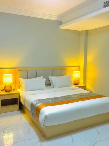 a bedroom with a large bed with two lamps at Abad Hotel in Mogadishu