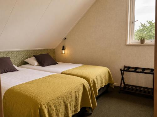 two beds in a room with yellow sheets and a window at De Veurdeale in Havelte