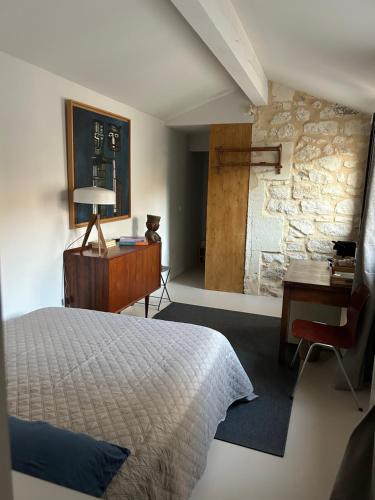 a bedroom with a bed and a desk and a stone wall at Maison Cerise in Arles