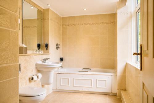 a bathroom with a toilet and a sink and a tub at Macdonald Berystede Hotel & Spa in Ascot