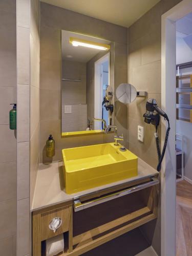 a yellow sink in a bathroom with a mirror at HIAMO Hotel Hamburg-Bergedorf in Hamburg